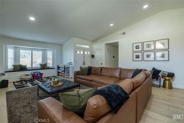 living room with light hardwood / wood-style floors and vaulted ceiling