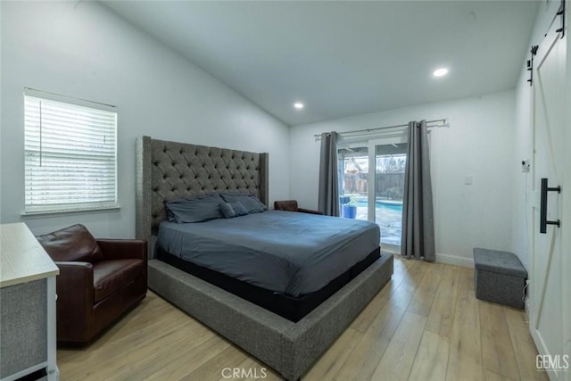 bedroom with a barn door, lofted ceiling, access to exterior, and light hardwood / wood-style flooring