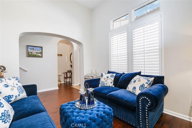 living area with arched walkways, wood finished floors, and baseboards