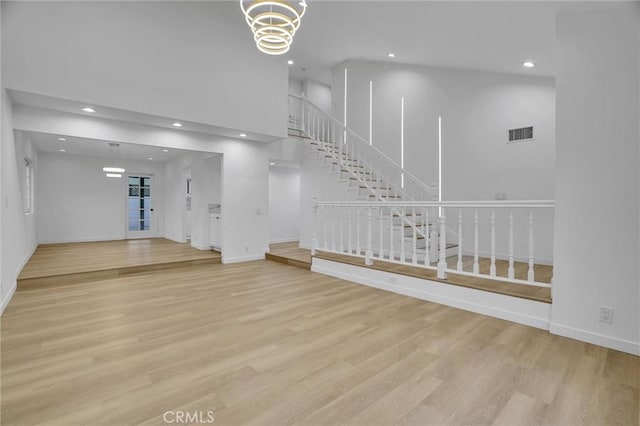 interior space with a chandelier, a high ceiling, and light wood-type flooring