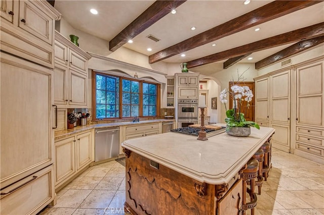22931 Sonriente Trl, Coto De Caza, CA 92679 - kitchen with stainless steel appliances, cream cabinets, arched walkways, recessed lighting, and beam ceiling