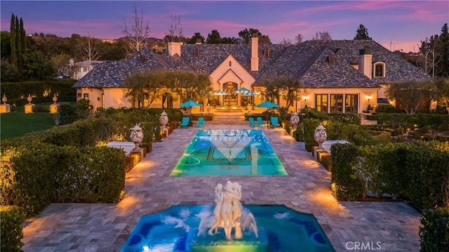 pool at dusk featuring a patio and an outdoor fire pit