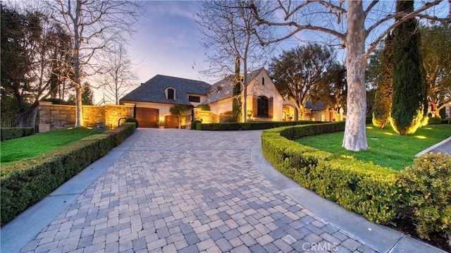 22931 Sonriente Trl, Coto De Caza, CA 92679 - french country style house with decorative driveway, stone siding, a yard, an attached garage, and stucco siding
