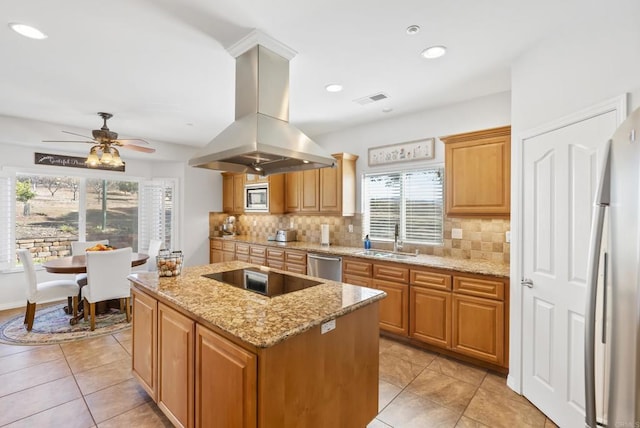 kitchen with light stone counters, a sink, appliances with stainless steel finishes, a center island, and island exhaust hood