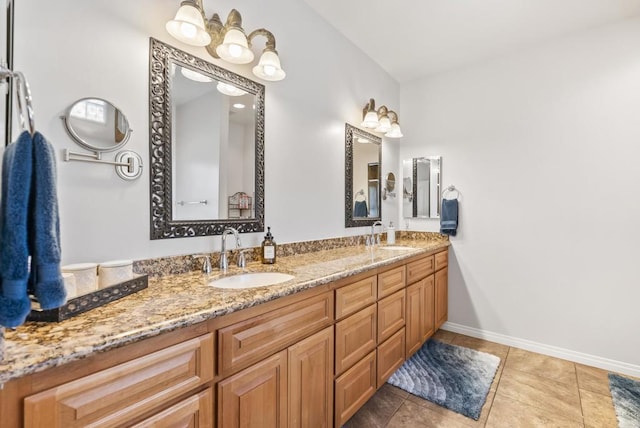 bathroom with double vanity, tile patterned floors, a sink, and baseboards