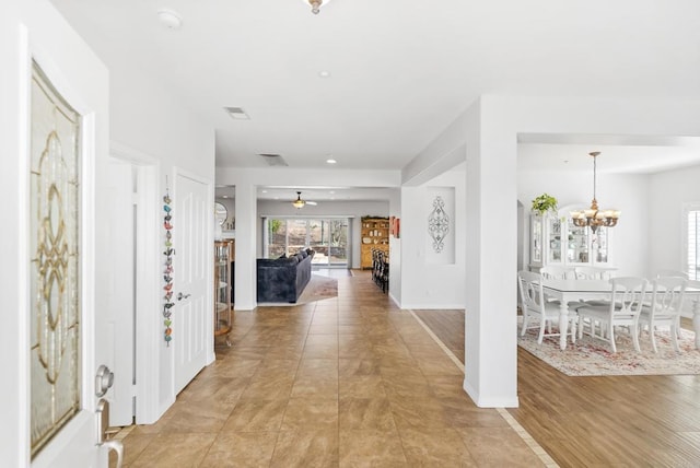 entryway featuring light wood-style floors, baseboards, and an inviting chandelier