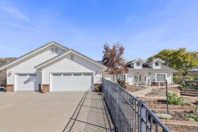 view of front of property with a garage, brick siding, driveway, and fence