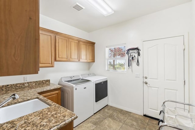 laundry area with a sink, visible vents, baseboards, cabinet space, and washer and clothes dryer