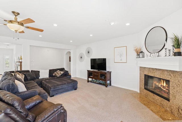 living room featuring arched walkways, light carpet, recessed lighting, and a premium fireplace