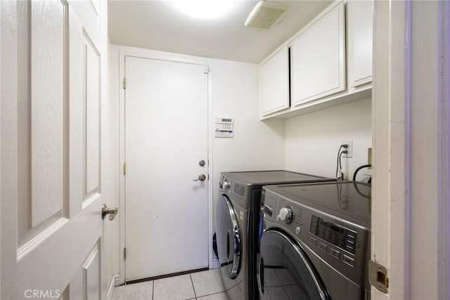 clothes washing area with cabinets, light tile patterned flooring, and separate washer and dryer