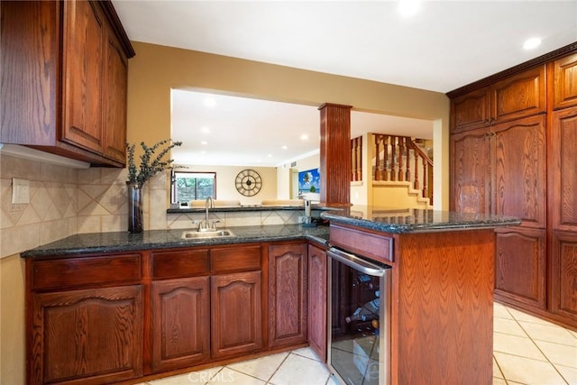 kitchen featuring sink, dark stone countertops, wine cooler, light tile patterned flooring, and kitchen peninsula