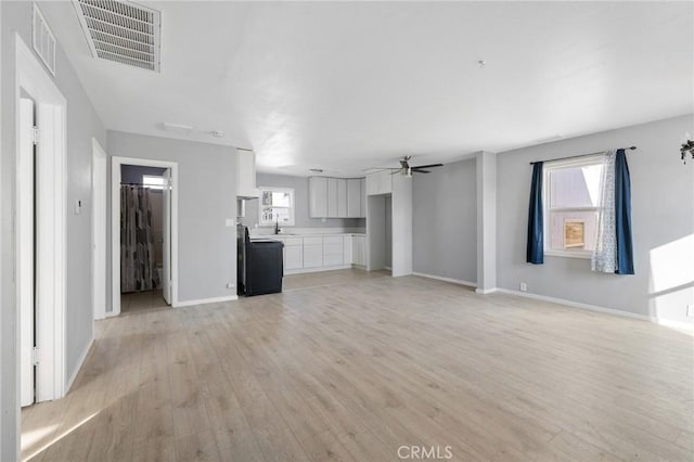 unfurnished living room with ceiling fan, sink, and light hardwood / wood-style flooring