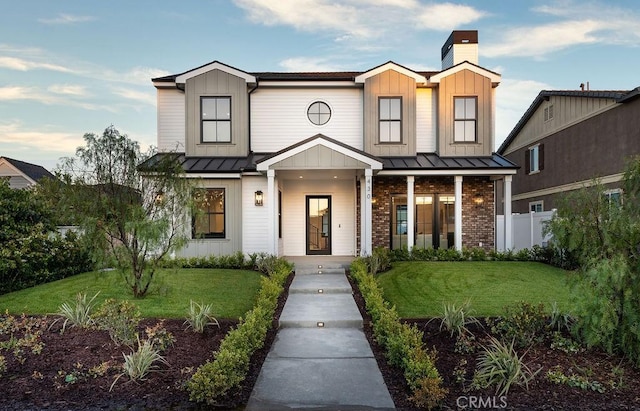 modern inspired farmhouse with a front yard and covered porch