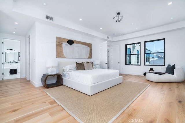 bedroom with connected bathroom and light hardwood / wood-style flooring