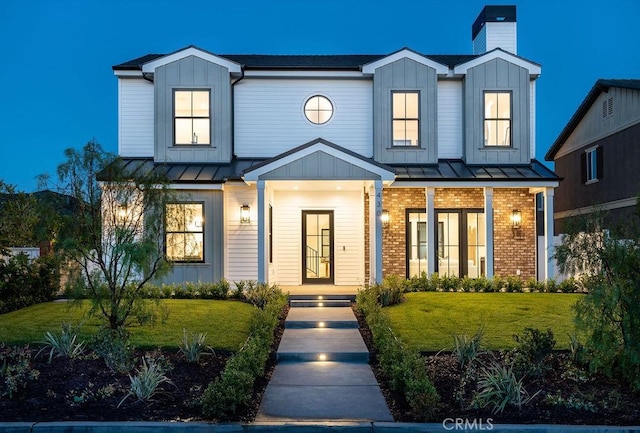 modern farmhouse style home with a standing seam roof, board and batten siding, and brick siding