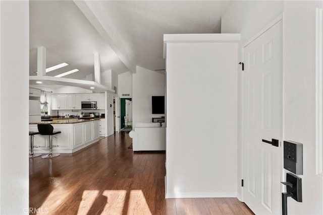 20095 Shadow Island Dr, Canyon Country, CA 91351 - kitchen featuring dark wood-type flooring, white cabinetry, a kitchen bar, vaulted ceiling, and white fridge