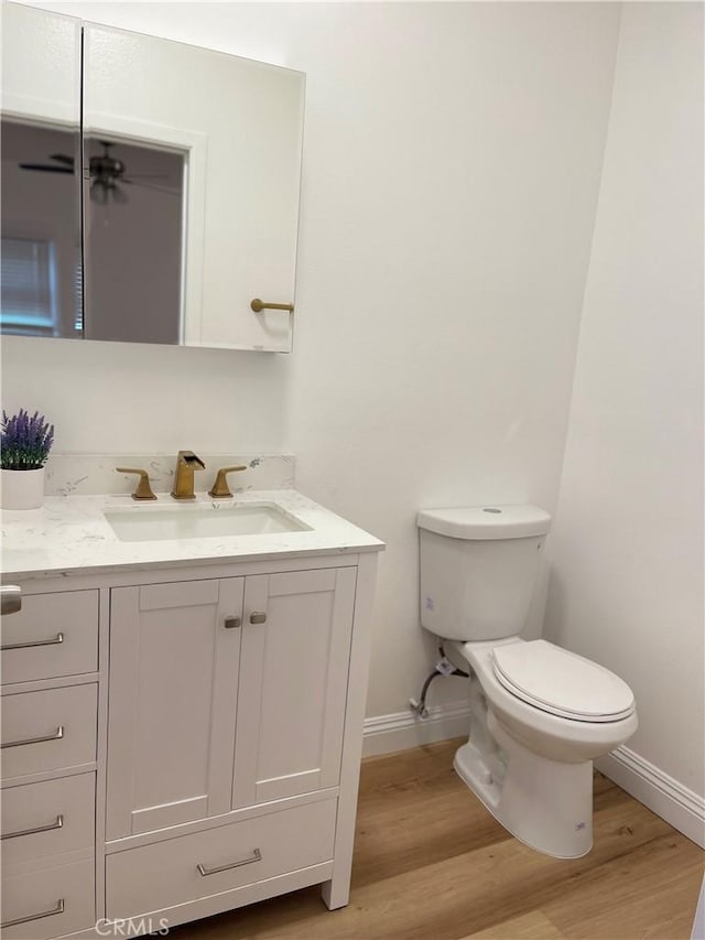 bathroom featuring toilet, wood finished floors, vanity, and baseboards