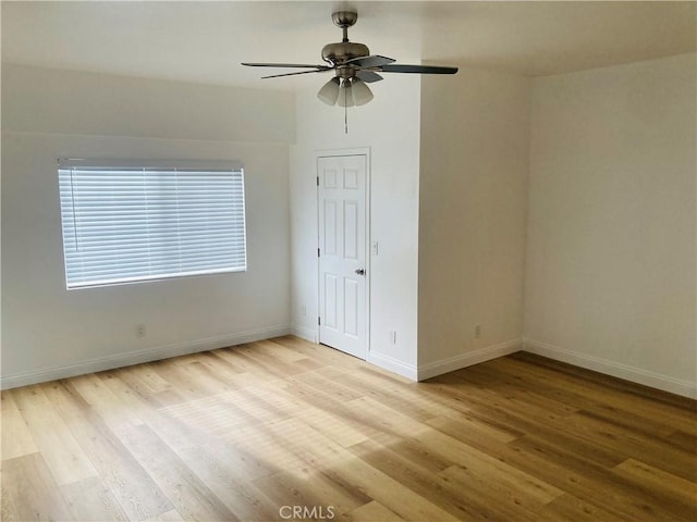 empty room with baseboards, ceiling fan, and light wood finished floors