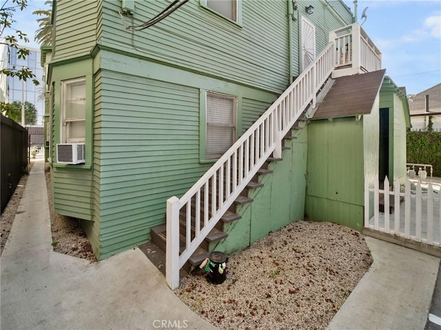 view of side of property with cooling unit, fence, and stairway