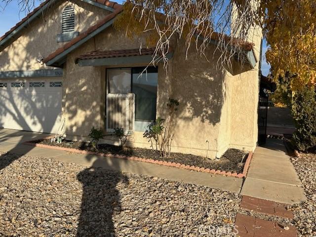 view of side of property with a tiled roof, a garage, and stucco siding