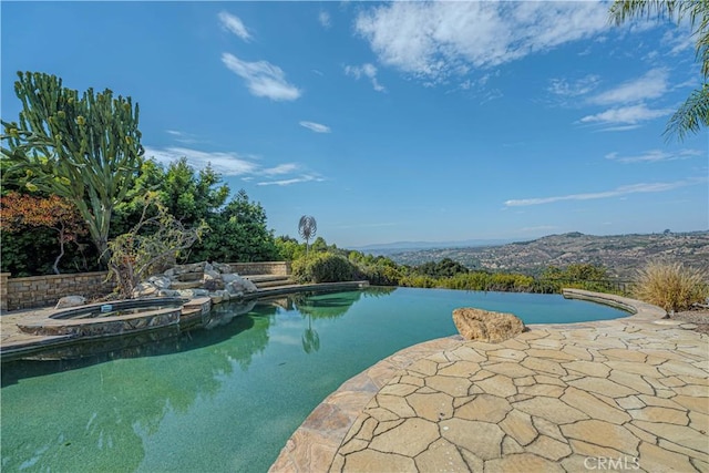 view of swimming pool with an in ground hot tub, a water and mountain view, and a patio