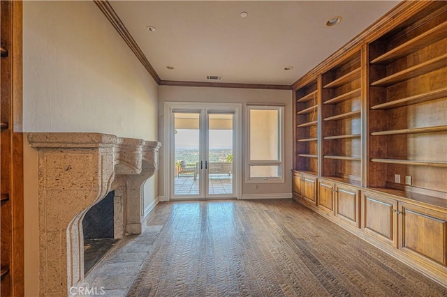 unfurnished living room featuring french doors, ornamental molding, a fireplace, and built in shelves