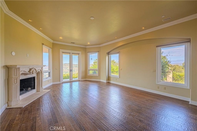 unfurnished living room featuring hardwood / wood-style floors, crown molding, a high end fireplace, and french doors