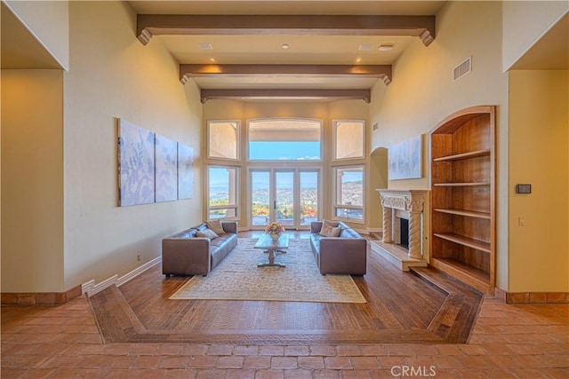 living room with beamed ceiling, a towering ceiling, built in features, and french doors