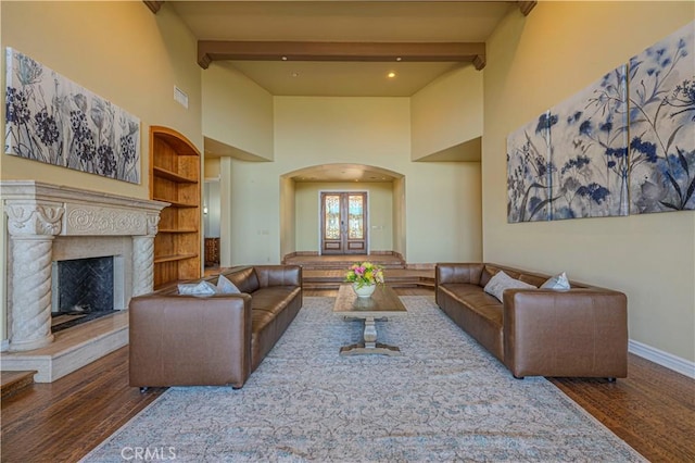 living room with dark hardwood / wood-style flooring, a high end fireplace, and beam ceiling