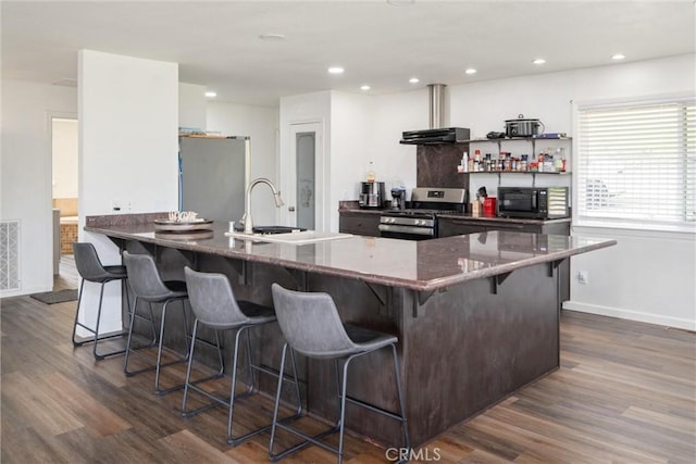 kitchen featuring sink, a kitchen breakfast bar, kitchen peninsula, stainless steel appliances, and dark wood-type flooring