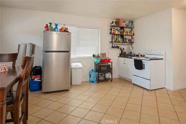 kitchen featuring white cabinetry, white electric range oven, stainless steel refrigerator, and light tile patterned floors