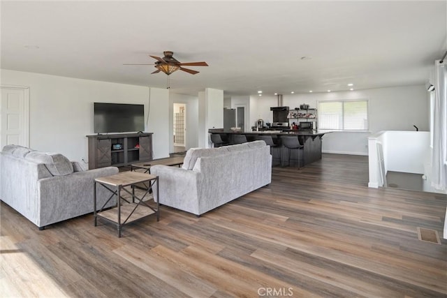 living room featuring ceiling fan and dark hardwood / wood-style flooring