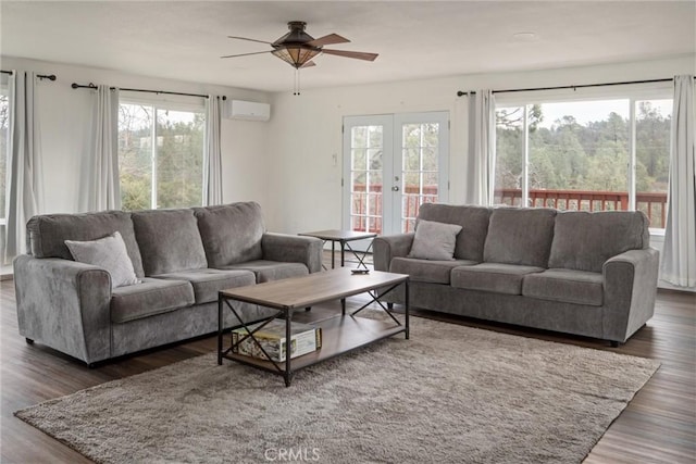 living room featuring dark wood-type flooring, a wall mounted air conditioner, ceiling fan, and french doors