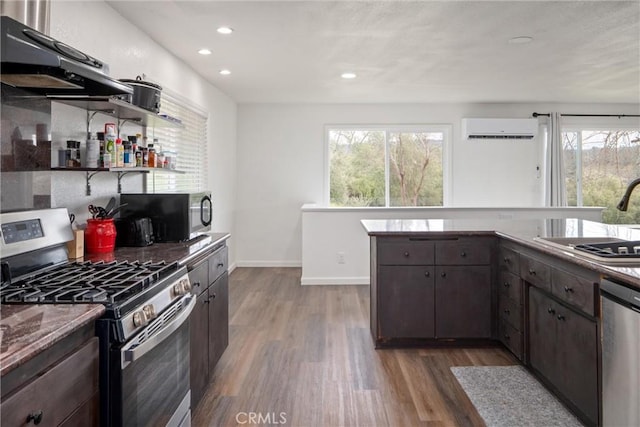 kitchen featuring dark brown cabinetry, sink, a wall mounted AC, appliances with stainless steel finishes, and dark hardwood / wood-style flooring