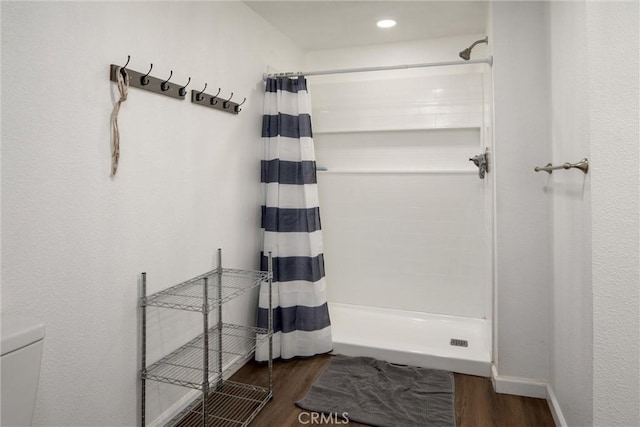 bathroom with wood-type flooring, toilet, and a shower with shower curtain