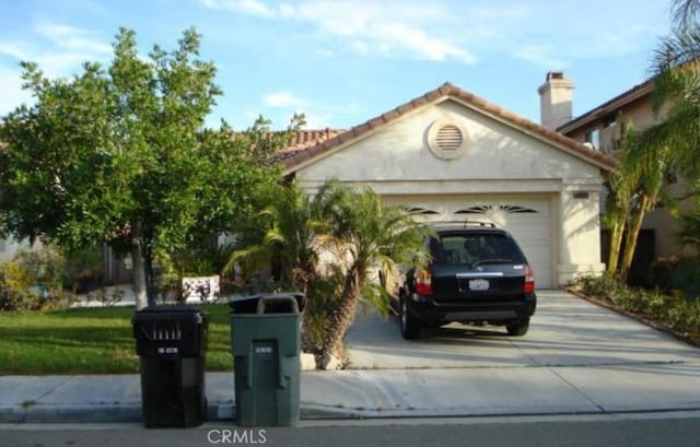 view of front of house featuring a garage, concrete driveway, and a tiled roof