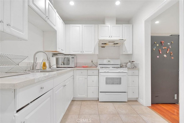 kitchen featuring white cabinetry, sink, range hood, and white gas stove