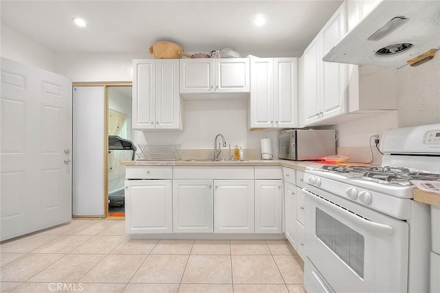 kitchen featuring sink, light tile patterned floors, white gas range oven, range hood, and white cabinets