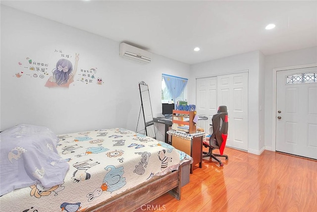 bedroom with a wall mounted AC, light hardwood / wood-style floors, and a closet