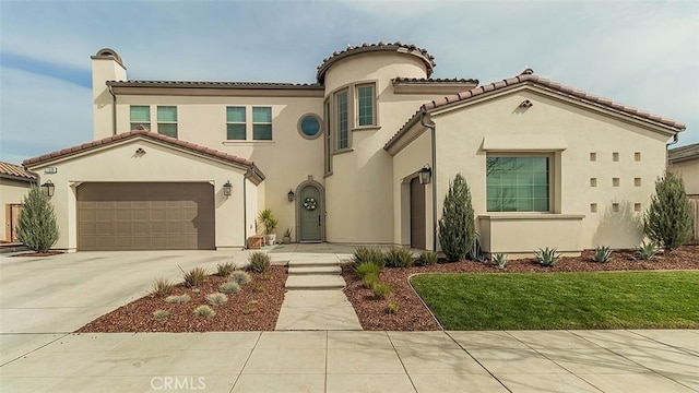 mediterranean / spanish house with driveway, a chimney, stucco siding, a garage, and a tiled roof