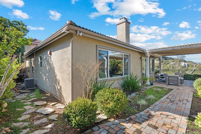 view of home's exterior with a pergola, cooling unit, and a patio area