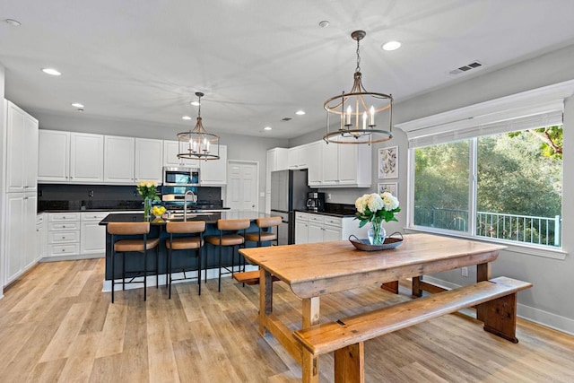 dining room featuring an inviting chandelier, sink, and light wood-type flooring