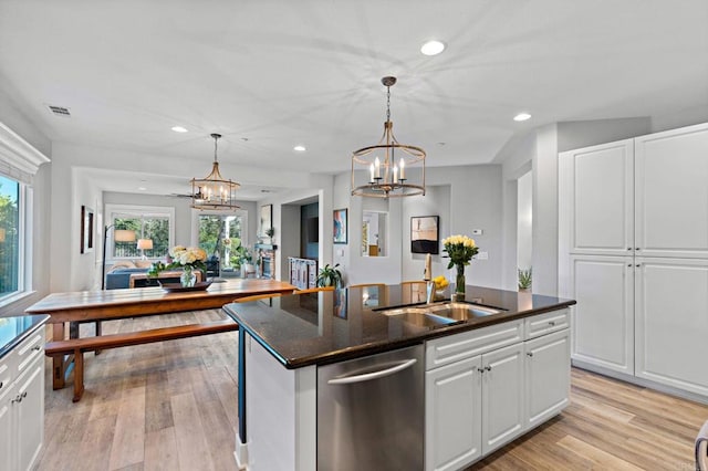 kitchen featuring white cabinetry, a chandelier, hanging light fixtures, stainless steel dishwasher, and an island with sink