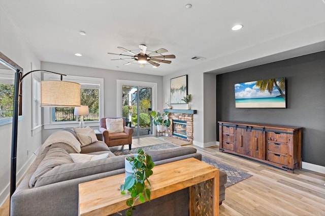 living room featuring light hardwood / wood-style flooring, a fireplace, a wealth of natural light, and ceiling fan