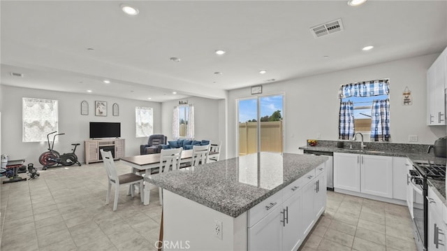 kitchen with appliances with stainless steel finishes, sink, a kitchen island, and white cabinets