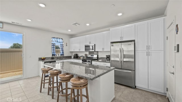 13180 Mesa Ln, Yucaipa, CA 92399 - kitchen with appliances with stainless steel finishes, a kitchen island, white cabinetry, dark stone countertops, and a breakfast bar area