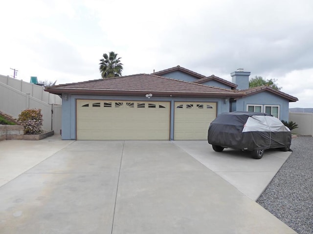 single story home with concrete driveway, a tiled roof, an attached garage, fence, and stucco siding