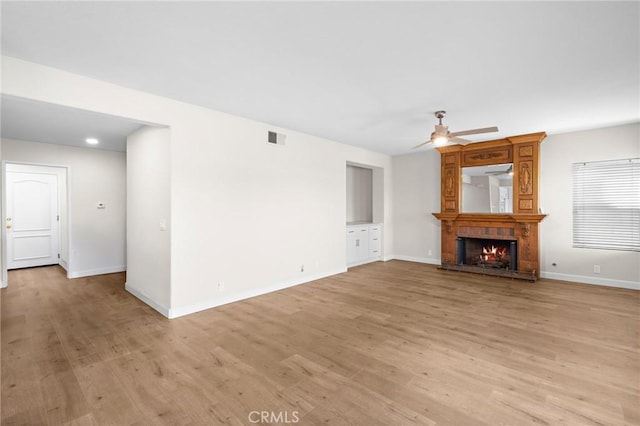 unfurnished living room featuring visible vents, baseboards, light wood-type flooring, a fireplace, and a ceiling fan