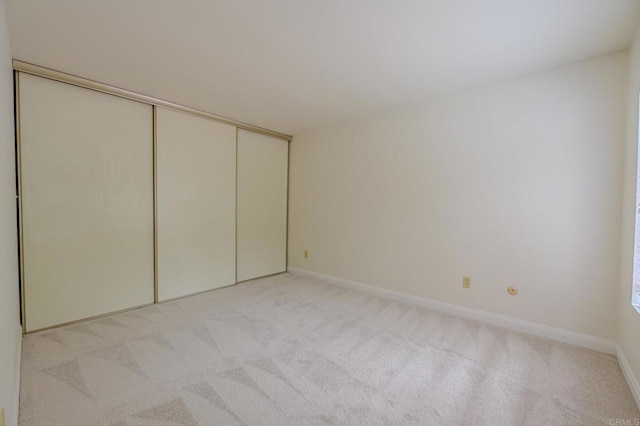 unfurnished bedroom featuring light colored carpet and a closet