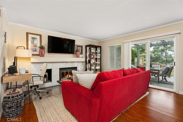 living room with crown molding, a fireplace, and wood finished floors